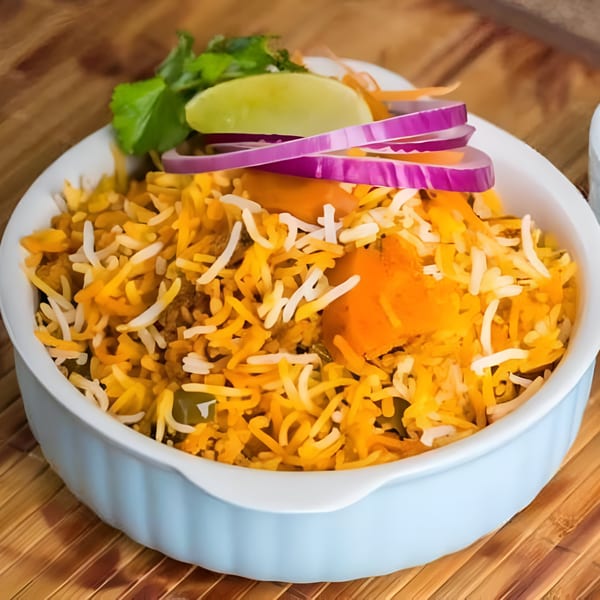 Bawarchi Biryanis' Indian biryani with rice, vegetables, lime, and red onions in a light blue bowl.